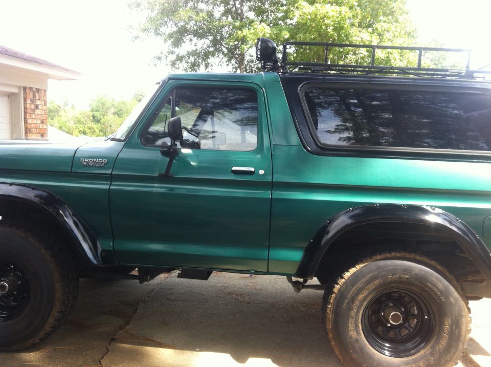 Green 1978 Ford Bronco side view with roof rack and off-road tires