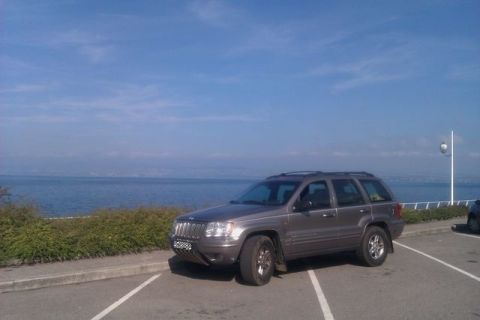 1991 Ford LTD Crown Victoria - A Jeep Grand Cherokee is parked in a lot overlooking a large body of water under a blue sky.