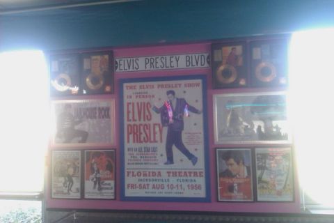 1991 Ford LTD Crown Victoria - A wall decorated with Elvis Presley posters and gold records, including a concert poster from 1956.