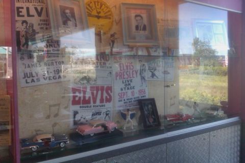 1991 Ford LTD Crown Victoria - Display case filled with Elvis Presley memorabilia, including posters and model cars.