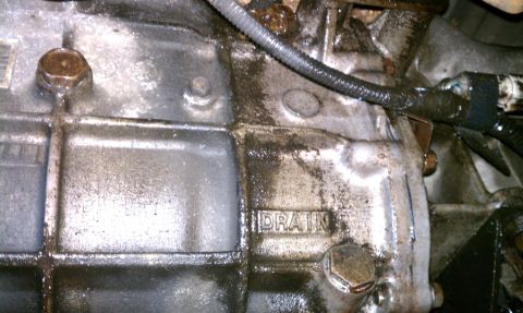 1990 Ford Bronco - Transmission casing shows signs of an oil leak, with the word DRAIN stamped into the metal.