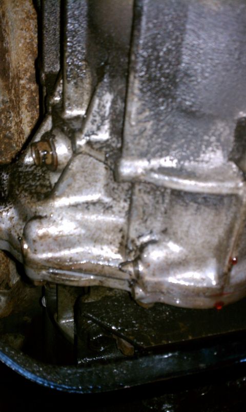 1990 Ford Bronco - Close-up of a transmission housing showing signs of a fluid leak.