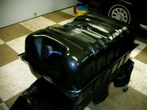 1990 Ford Bronco - A freshly painted fuel tank is shown, with a partial view of a vehicle in the background.
