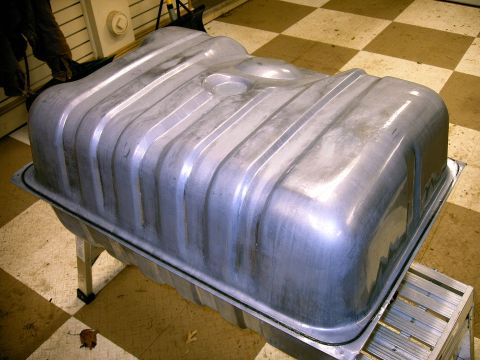 1990 Ford Bronco - A metal fuel tank with ribbed sides and a black gasket is shown, resting on a silver stand.