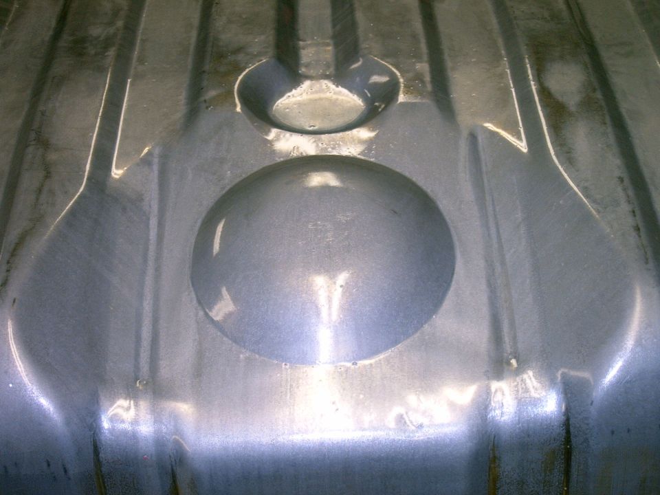 Close-up of the interior of a metal fuel tank with embossed circular and oval shapes