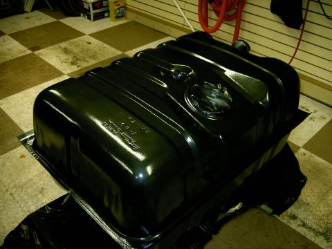 1990 Ford Bronco - A black fuel tank is shown, possibly for a Ford Bronco, with visible embossed text and a circular emblem.