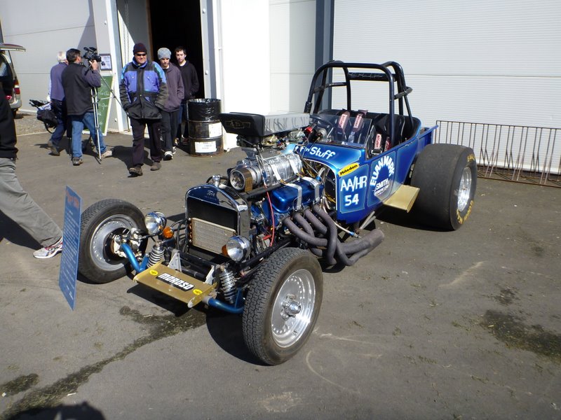 Blue dragster with supercharger, roll cage, and large rear tires. Text on side reads 'AAHR 54'