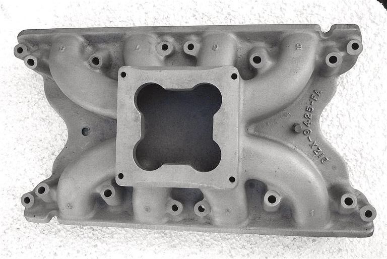 Aluminum intake manifold with a square carburetor mounting flange and eight intake ports. Casting numbers visible include D1ZX-9425-FA