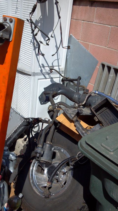 1990 Ford Bronco - A collection of engine parts and a tire are piled up, with a Supermotors.net logo visible at the bottom.