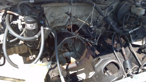 1990 Ford Bronco - The engine bay is partially disassembled, with the transmission removed and various hoses and lines visible.