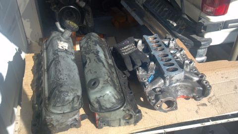 1990 Ford Bronco - Engine parts including valve covers and intake manifold are displayed on wooden planks.