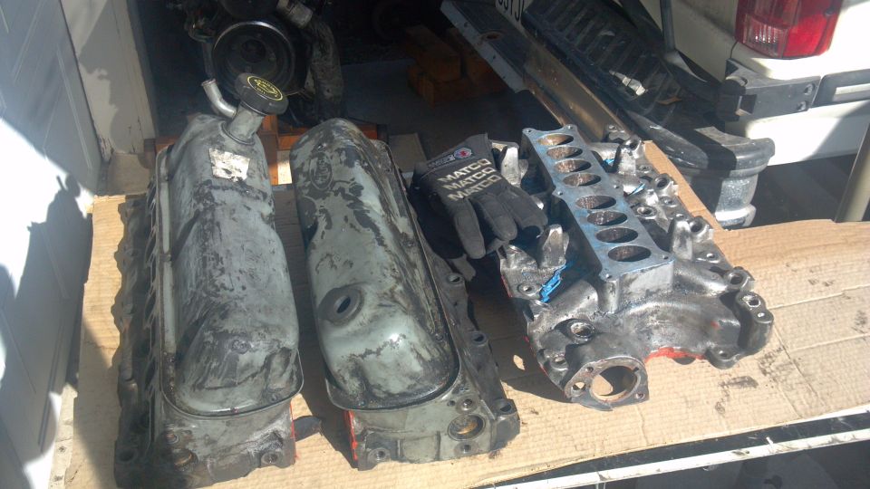 Engine valve covers and intake manifold laid out on wooden planks