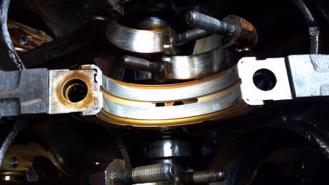 1990 Ford Bronco - Close-up view of worn engine crankshaft bearings, indicating a need for replacement during an engine rebuild.