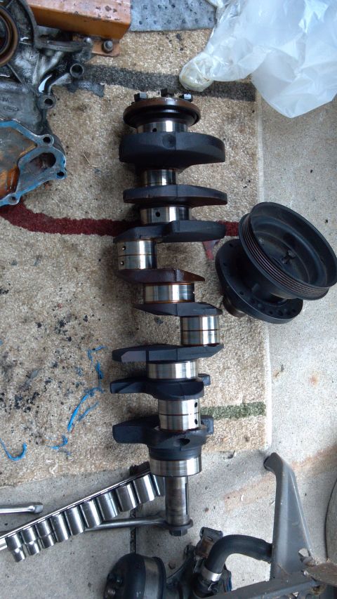 1990 Ford Bronco - A disassembled engine crankshaft and pulley are laid out on a rug with various tools nearby.