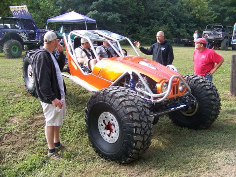 2001 Dodge 1500 - An orange off-road buggy is parked on grass with people around it.