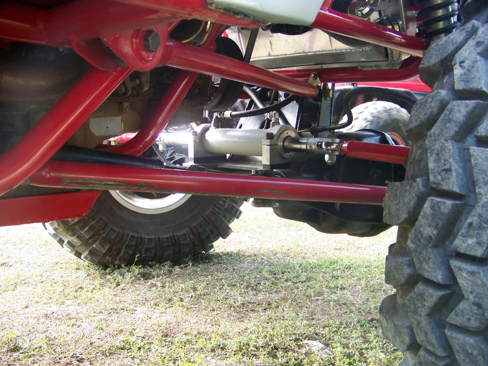 Off-road vehicle suspension with red tubing, large tire, and hydraulic steering component
