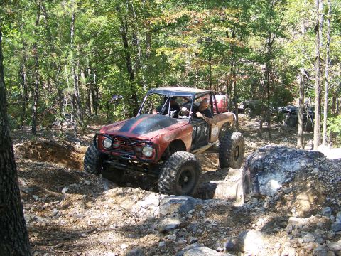 2001 Dodge 1500 - This heavily modified off-road vehicle is tackling a challenging rocky terrain in a wooded area.