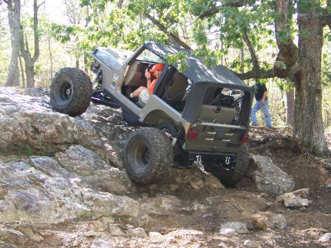 2001 Dodge 1500 - A modified Jeep Wrangler navigates a rocky off-road course with a person watching in the background.