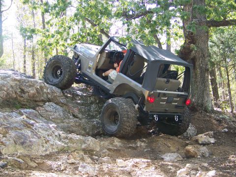2001 Dodge 1500 - A Jeep Wrangler navigates a rocky trail in a wooded area.