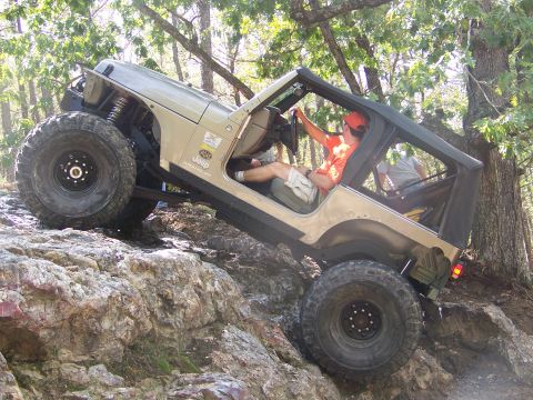 2001 Dodge 1500 - A tan Jeep Wrangler navigates a rocky trail with a driver wearing an orange hat.