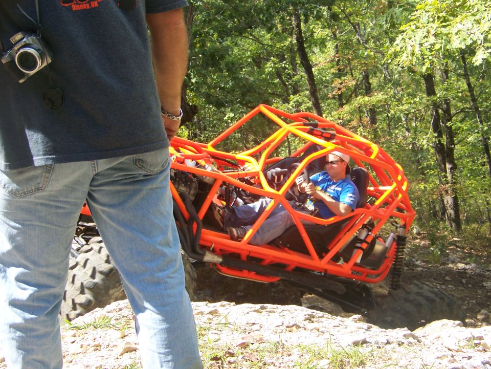 Orange off-road buggy with driver on rocky terrain