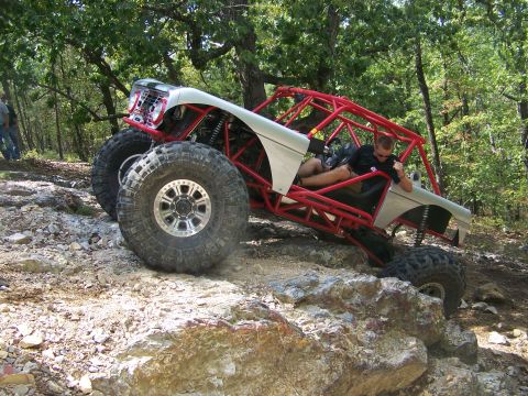 2001 Dodge 1500 - A heavily modified off-road vehicle navigates a rocky trail with a driver inside.