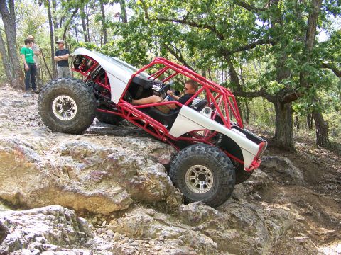 2001 Dodge 1500 - A custom-built buggy navigates a rocky off-road course with spectators watching.