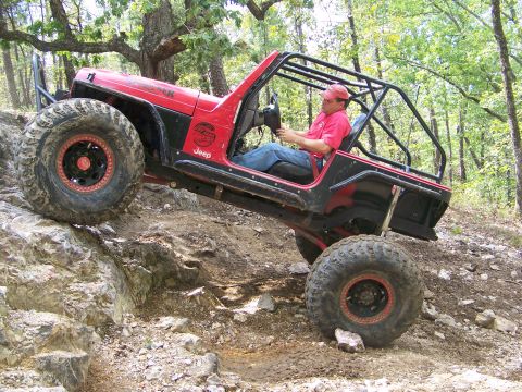 2001 Dodge 1500 - A red Jeep Wrangler navigates a challenging rocky trail during an off-road excursion.