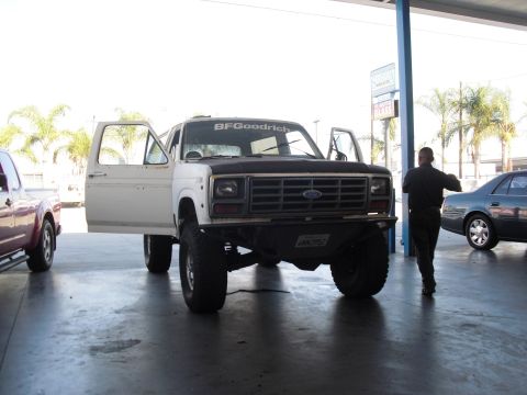 1986 Ford Bronco - White Ford Bronco with doors open, parked indoors with other vehicles nearby.