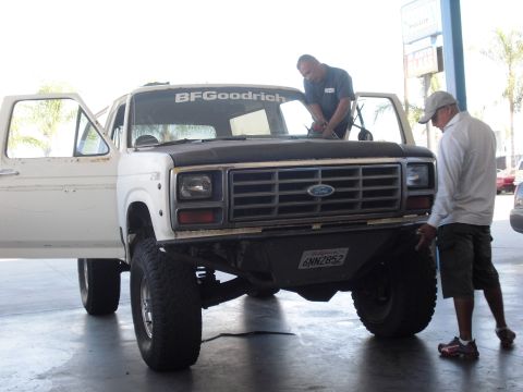 1986 Ford Bronco - Two men are working on a white Ford Bronco with its hood open and doors ajar.