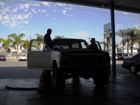 1986 Ford Bronco - Two people are working on a 1986 Ford Bronco inside a garage.