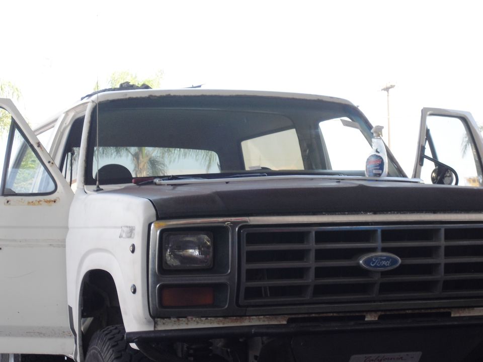 Front view of a white Ford Bronco with doors open. Grille has horizontal bars and a Ford logo
