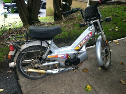 1999 Tomos Targa - A silver moped with 'TOMOS' and 'TARGA' graphics is parked on a concrete surface.