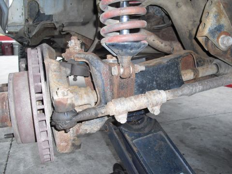 1986 Ford Bronco - Close-up view of heavily rusted vehicle suspension components, including a coil spring and brake rotor.