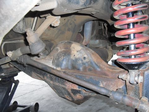 1986 Ford Bronco - Undercarriage view of a vehicle's rear axle and suspension system, showing rust and wear.