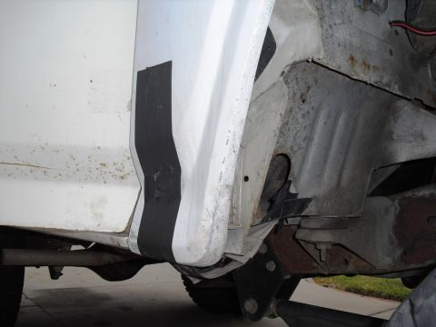 1986 Ford Bronco - Detail of the rear wheel well on a white 1986 Ford Bronco, showing some rust and black trim.