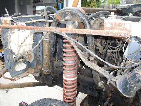 1986 Ford Bronco - Front suspension and engine details of a 1986 Ford Bronco, prominent red coil springs and exposed engine components.