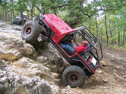 2001 Dodge 1500 - A heavily modified red Jeep navigates a challenging rocky terrain, with another off-road vehicle visible in the background.