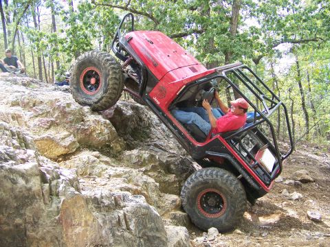 2001 Dodge 1500 - A red Jeep Wrangler navigates a steep, rocky trail with a driver at the wheel.