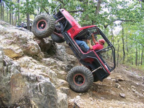 2001 Dodge 1500 - A red Jeep navigates a steep, rocky incline on an off-road trail.