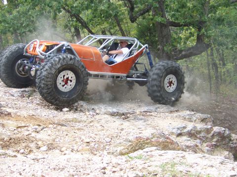 2001 Dodge 1500 - A custom-built off-road buggy navigates a rocky terrain with dust kicking up from its tires.