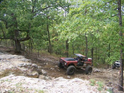 2001 Dodge 1500 - Two off-road vehicles navigate a wooded, rocky terrain.