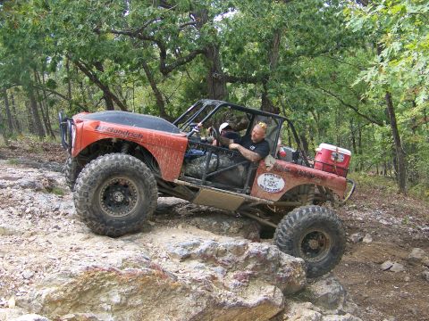 2001 Dodge 1500 - A heavily modified off-road buggy navigates a rocky trail in a wooded environment.