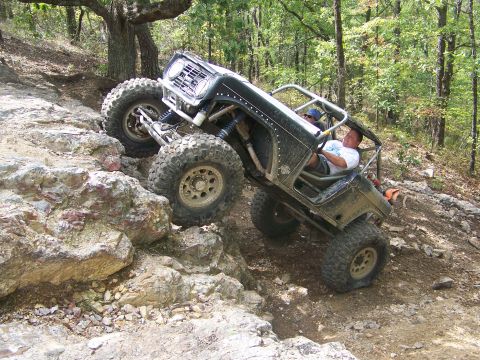 2001 Dodge 1500 - A heavily modified off-road vehicle navigates a challenging rocky trail, demonstrating its extreme suspension and tire capabilities.
