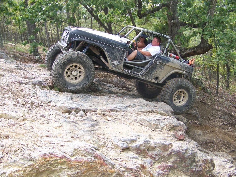 Modified off-road vehicle with large tires climbing a rocky incline