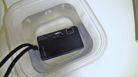 1993 Ford Taurus - A black Sony Cyber-shot digital camera is shown submerged in water within a clear plastic container.