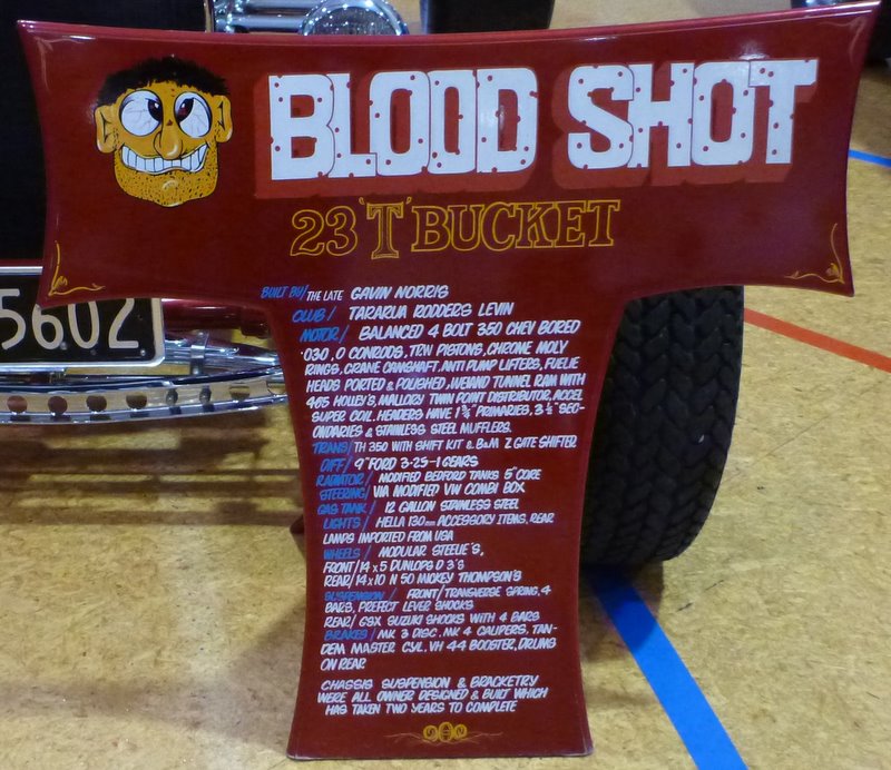 Red sign with 'BLOOD SHOT 23 T BUCKET' and build details for a hot rod