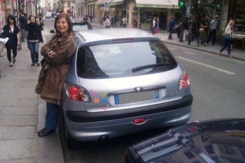 1991 Ford LTD Crown Victoria - A woman poses with a silver Peugeot 206 hatchback on a busy city street.