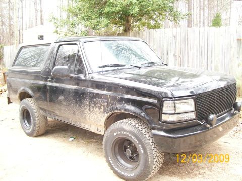 1996 Ford Bronco - Mud-splattered black 1996 Ford Bronco shown from a 3/4 front angle.