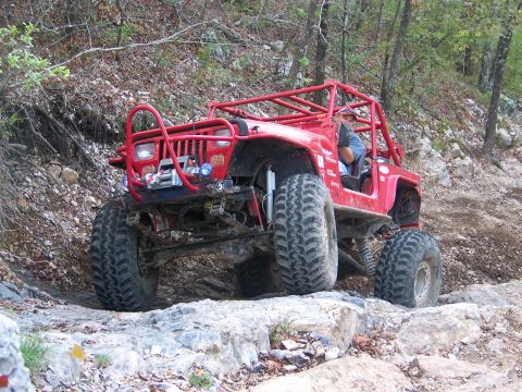 2001 Dodge 1500 - A modified Jeep navigates a challenging rocky terrain with a driver behind the wheel.